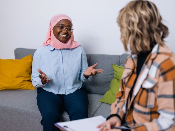 Two women engaged in a friendly conversation on a couch.