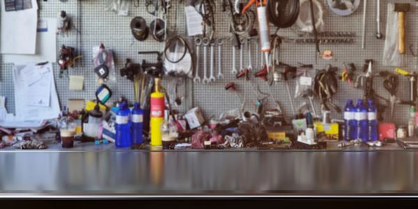 A cluttered workbench with tools and bottles arranged on a pegboard wall.