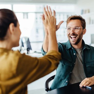 two colleagues in an office doing a high five