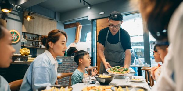 Server bringing food to family in restaurant.