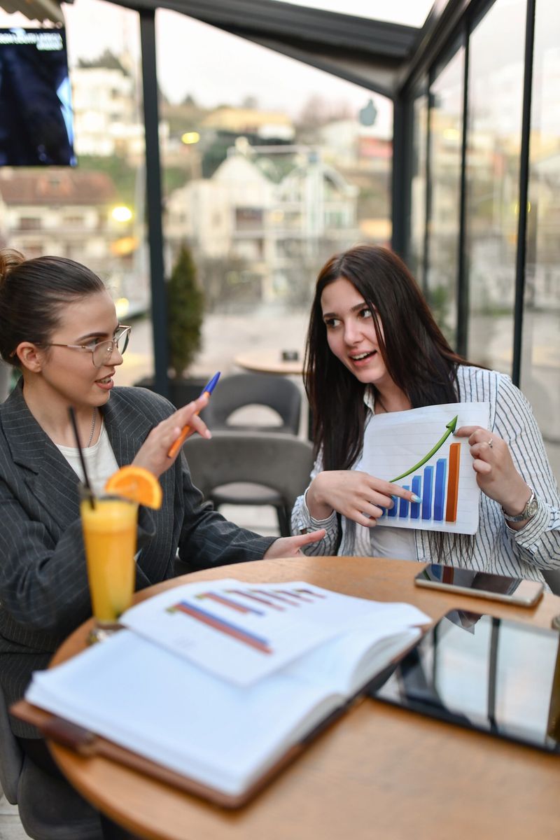 Two Businesswomen Debating Economics While Drinking Orange Juice During Work Break