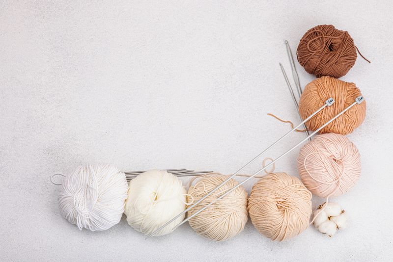 A set of pastel natural colors clews of thread for knitting and special craft tools. Handmade, hobby, crochet concept. Props and stuff on light stone concrete background, top view