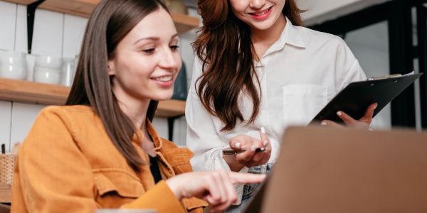 Two women happily discussing work on a laptop.