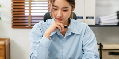 A young woman in a blue shirt focused on her work at a desk.