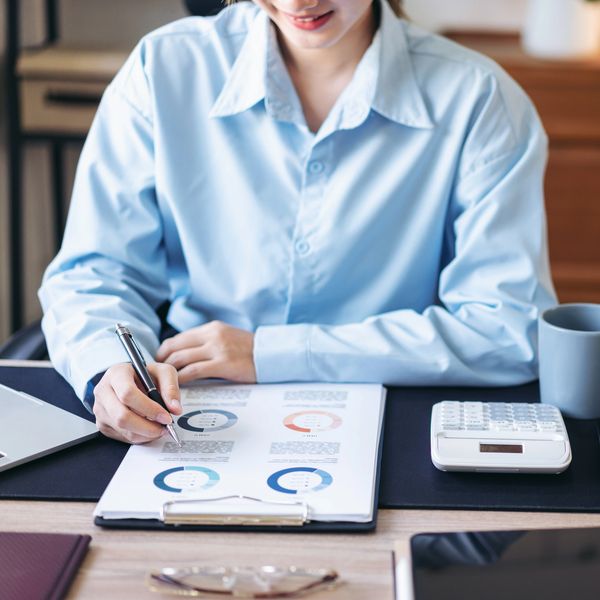Person analyzing charts and data with a pen at a desk.