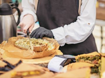 Person cutting a savory pie in a kitchen or bakery.