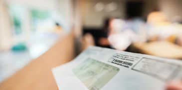 Close-up of a person holding a mail envelope with a blurred indoor background.