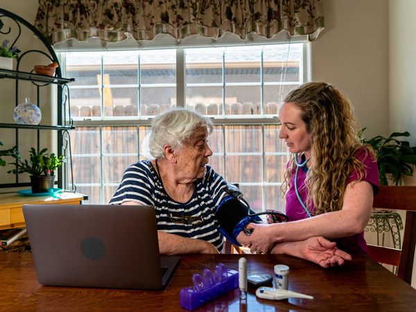 Female practitioner in the home of a female patient taking her blood pressure