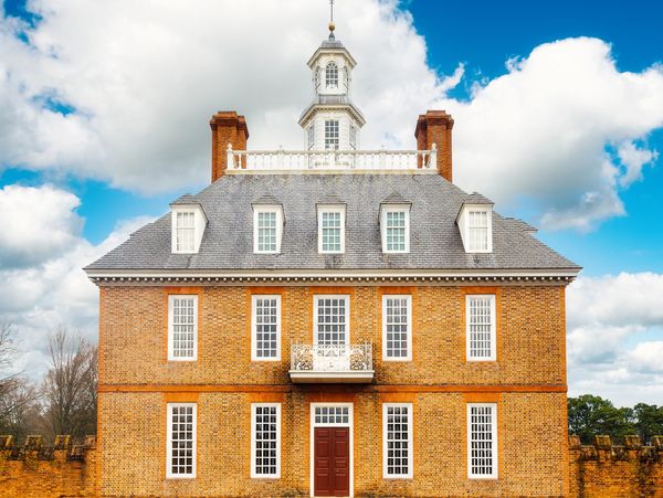 Historic brick building with white-framed windows under a partly cloudy sky.