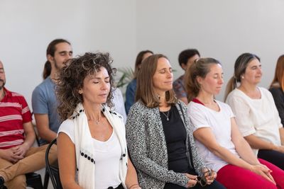 Group of professionals participating in a seated wellness session with eyes closed