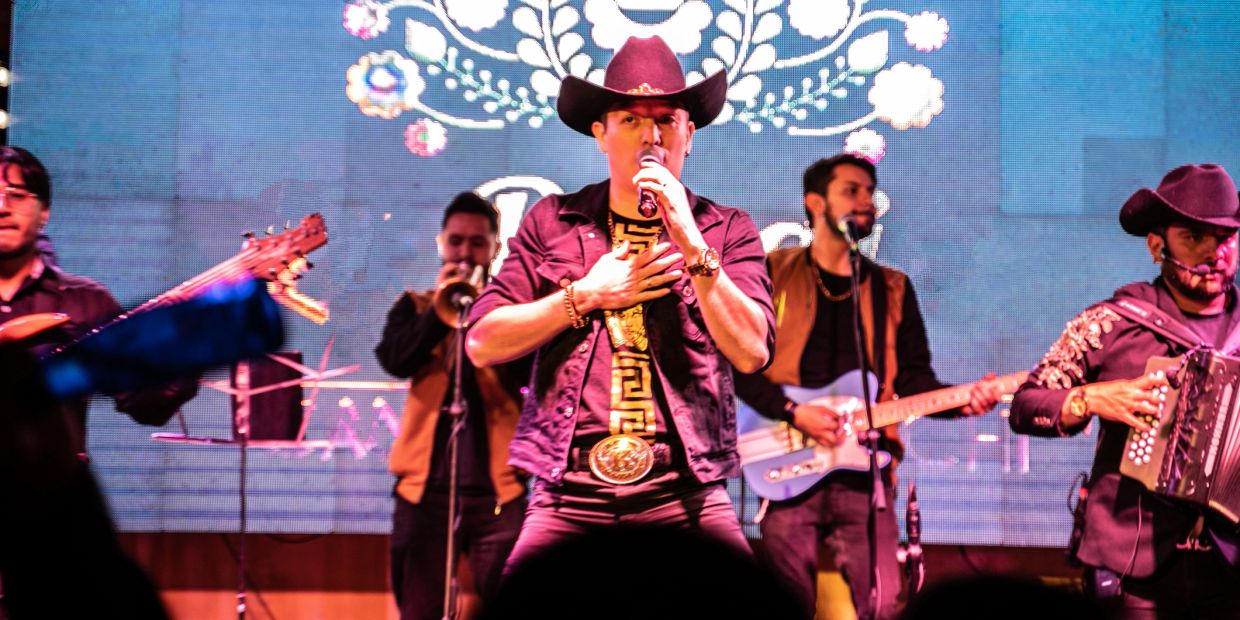 Male singer in a cowboy hat performing with band.