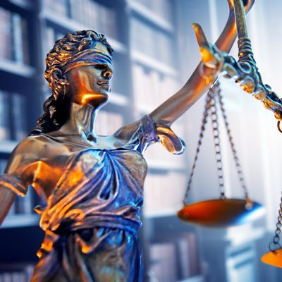 Statue of Lady Justice holding balance scales in a law library.