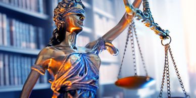 Statue of Lady Justice holding balance scales in a law library.