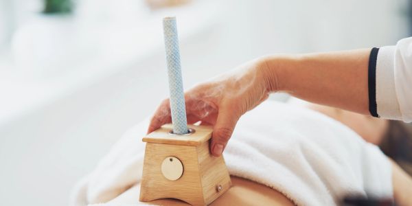 Hand holding a wooden device with a stick on a person's back.