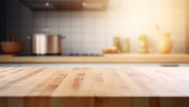 Empty wooden kitchen countertop with blurred background and soft sunlight.