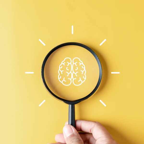 Magnifying glass highlighting a brain icon on a yellow background.