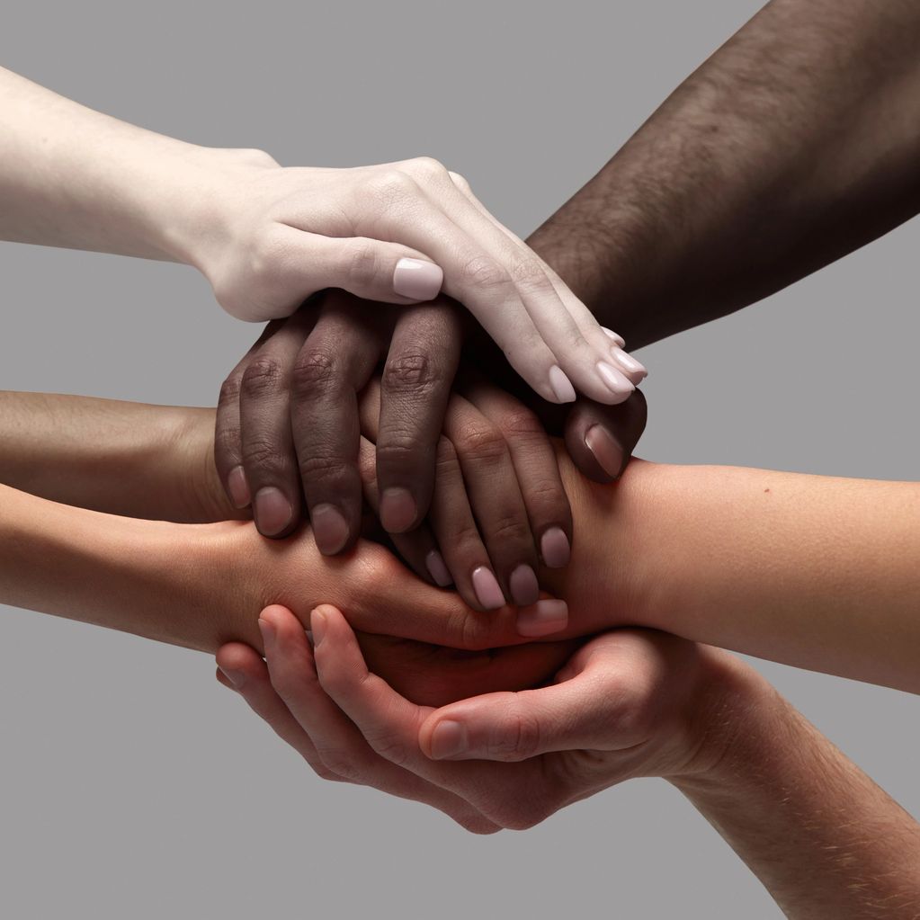 Diverse hands stacked together symbolizing unity and support.