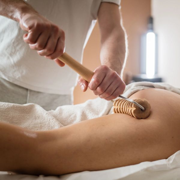 Therapist using a wooden massager on a person's back.