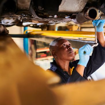 Mechanic working under a vehicle, tightening parts with a wrench.