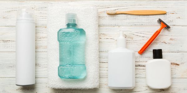 Personal hygiene items including a razor, toothbrush, and bottles on a wooden surface.