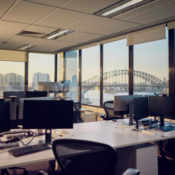 Modern office with computer workstations and a view of Sydney Harbour Bridge.