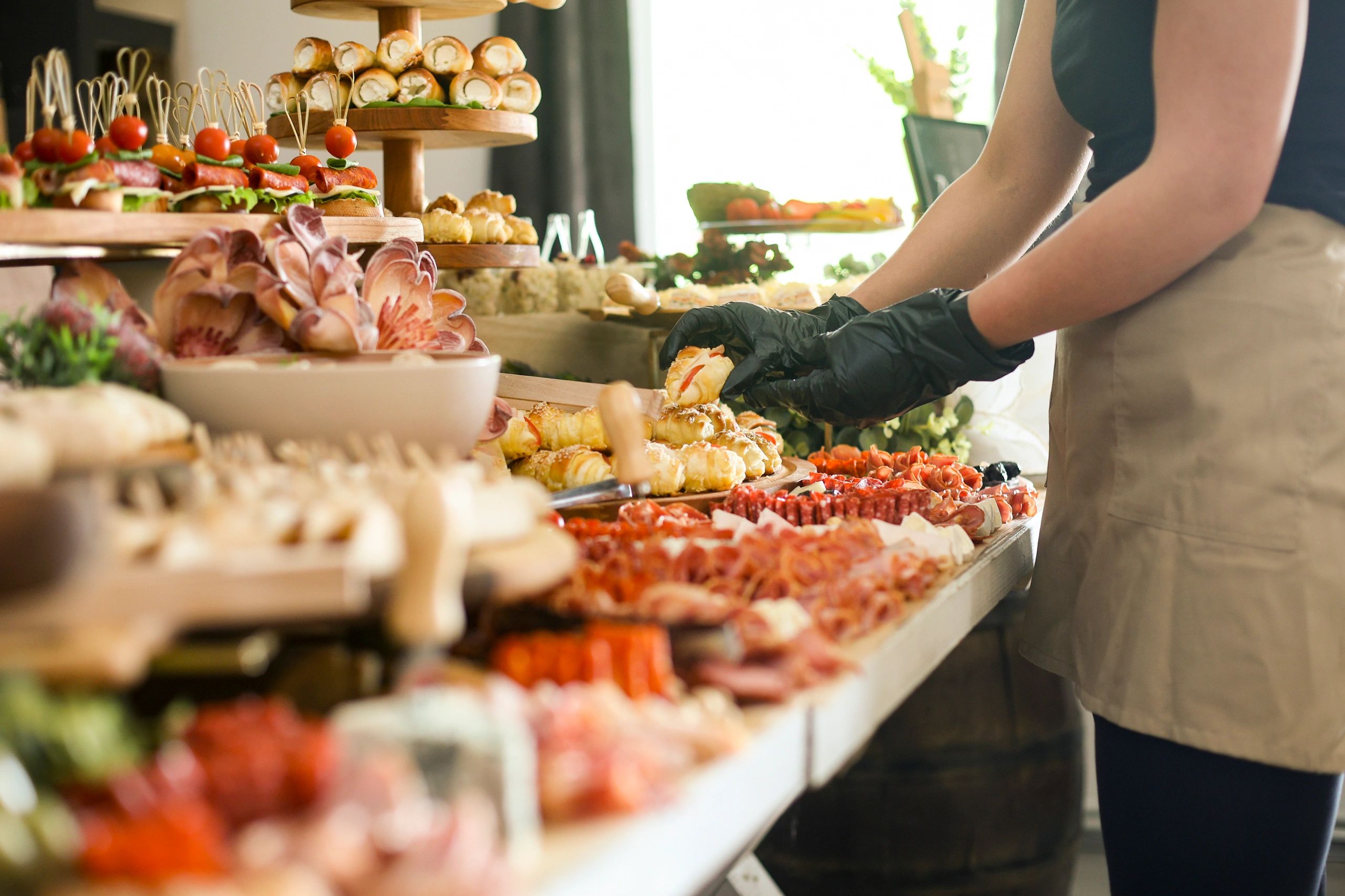 Person arranging assorted appetizers at a catering event.