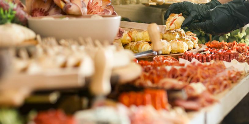 Close-up of hand selecting food from a buffet table.