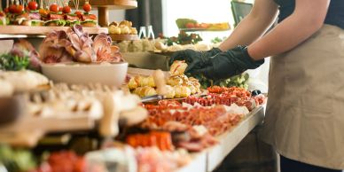 Person preparing a large spread of charcuterie and appetizers.