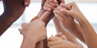 Multiple hands clasped together symbolizing unity and support.
