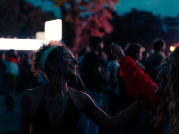 Two women enjoying a lively night event with colorful lighting.
