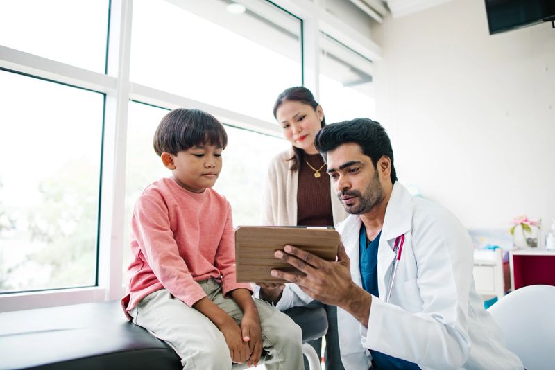 Asian Indian doctor is playing with Malay little patient for making him happy before  he is scare.