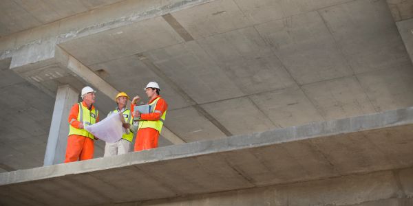 Three construction workers discussing plans at a building site.