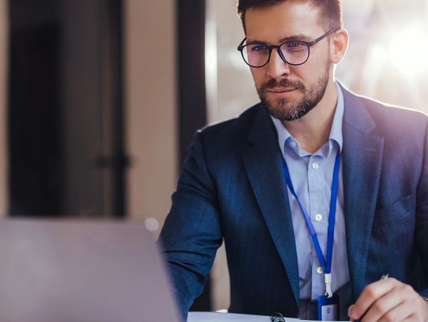 Focused businessman working on a laptop in an office environment.