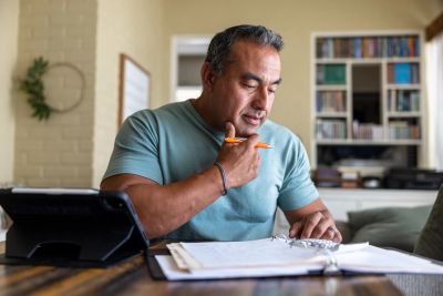 Man studying with books and tablet at home.