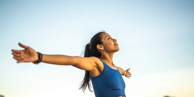 Woman in blue sportswear enjoying fresh air with arms wide open.