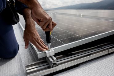 Technician securing a solar panel to an aluminium rooftop mounting rail.