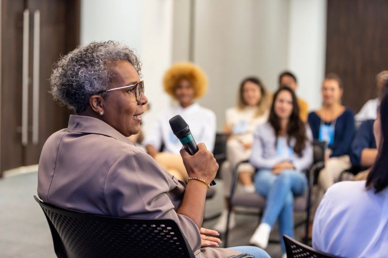 Black woman lecturing and audience in the background