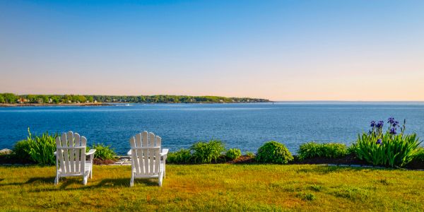 Two white chairs facing a peaceful ocean view.