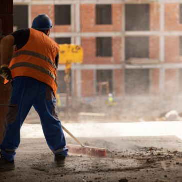 Construction worker sweeping debris at a building site.