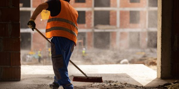 Worker sweeping construction site dirt.