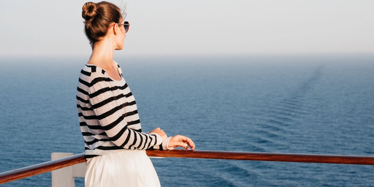 Woman on cruise ship deck looking out over the open sea.