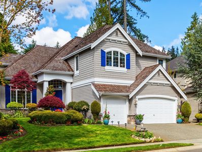 A charming two-story house with blue shutters and a well-kept garden.