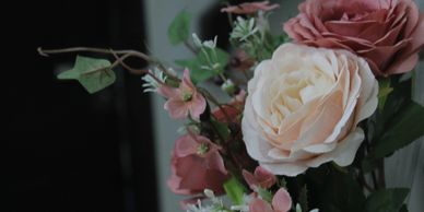 Close-up of a bouquet with white and pink roses and green leaves.
