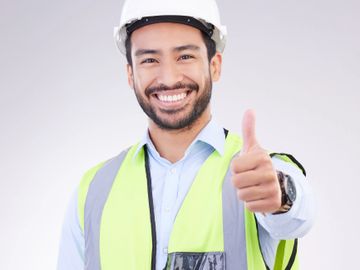 Smiling construction worker giving a thumbs-up gesture.