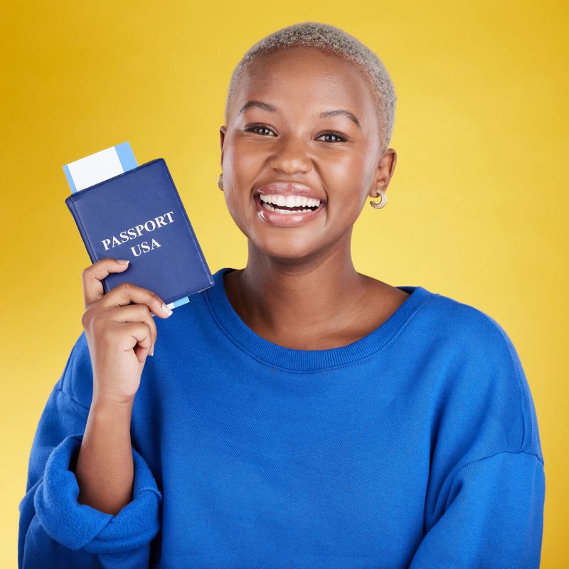 Happy woman face with passport isolated on yellow background for USA travel opportunity, immigration or holiday. Identity documents, flight ticket and excited portrait of young black person in studio
