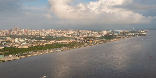 A city skyline along a wide river under cloudy skies.