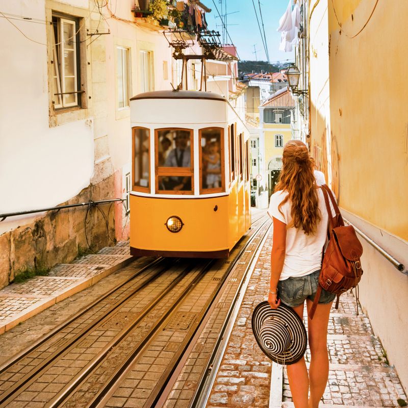 Traveler woman waiting yellow traditional tram on a street in Lisbon- Portugal