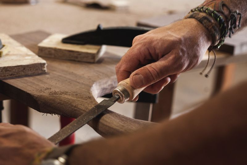 A close-up view of a skilled woodworker's hands meticulously shaping and rounding the wood using a file. Witness the artistry as every stroke brings the wood to its perfect form.