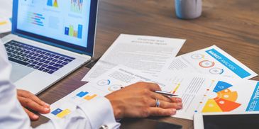 Person analyzing business charts and graphs with a laptop and documents.