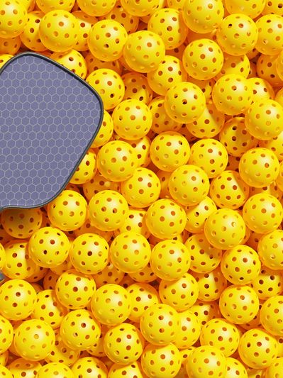 Two pickleball paddles on a pile of yellow pickleball balls.